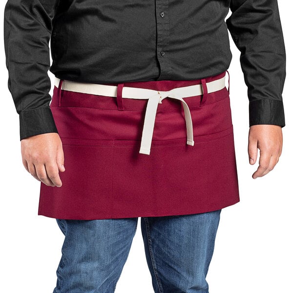 A man in a black shirt wearing a red Uncommon Chef waist apron with natural webbing.