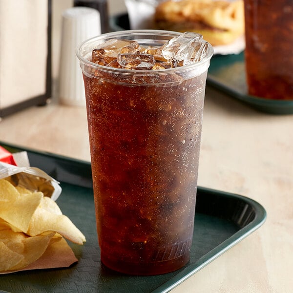 A plastic cup with ice and a brown drink on a tray.