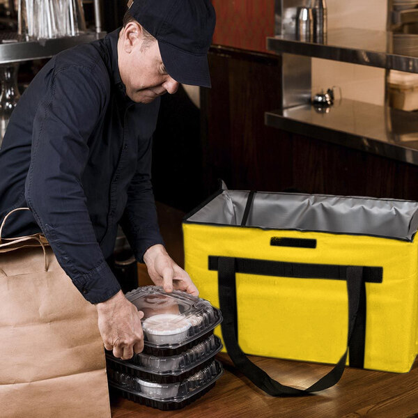 A man carrying a yellow Sterno insulated food delivery bag.