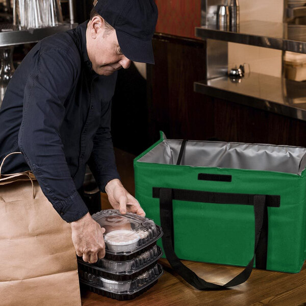 A man putting food in a Sterno green and black insulated food delivery bag.