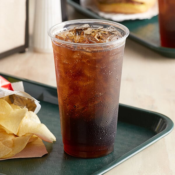 A plastic cup with a drink and a plate of chips.