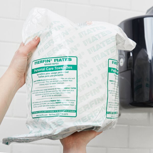 A person holding a plastic bag of Merfin Mates personal care wipes.