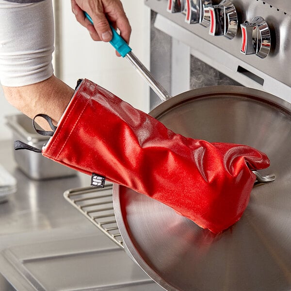 A person using a San Jamar red EZ-KLEEN oven mitt to clean a pan.