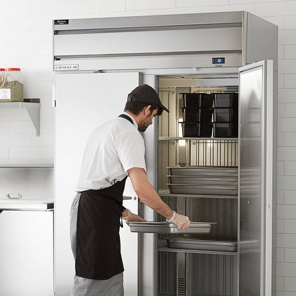Staff loading food pans into a Beverage-Air reach-in refrigerator