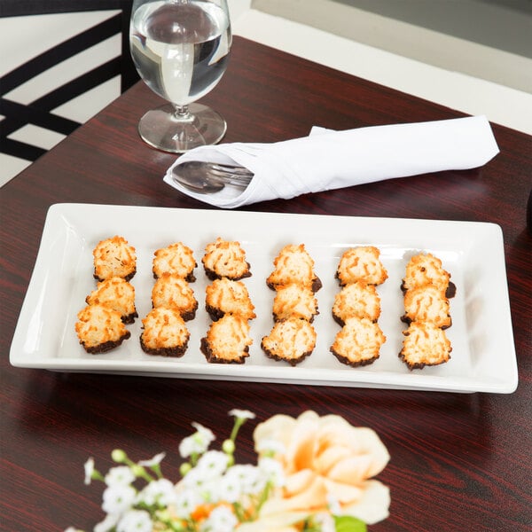 An American Metalcraft white rectangular stoneware platter with food on it on a table.