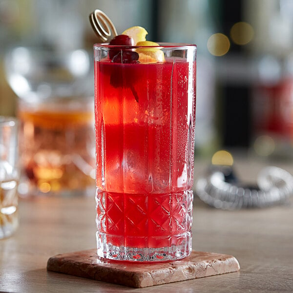 A close-up of an Acopa Evora highball glass with red liquid and fruit in it.