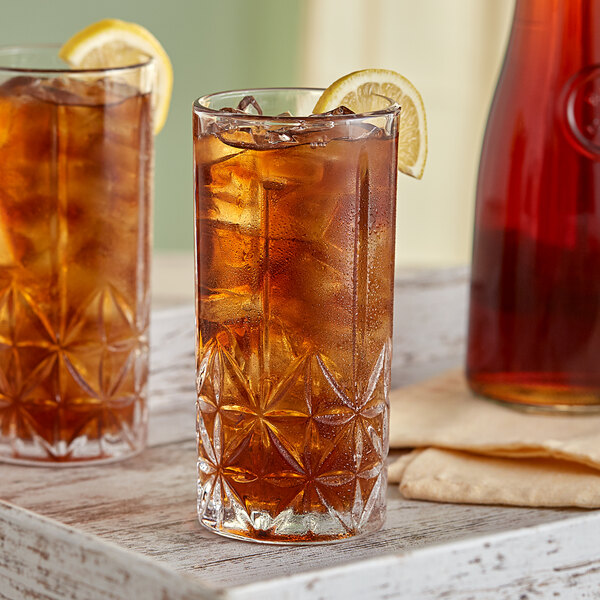 A close-up of an Acopa Gardenia highball glass filled with iced tea and a lemon slice.