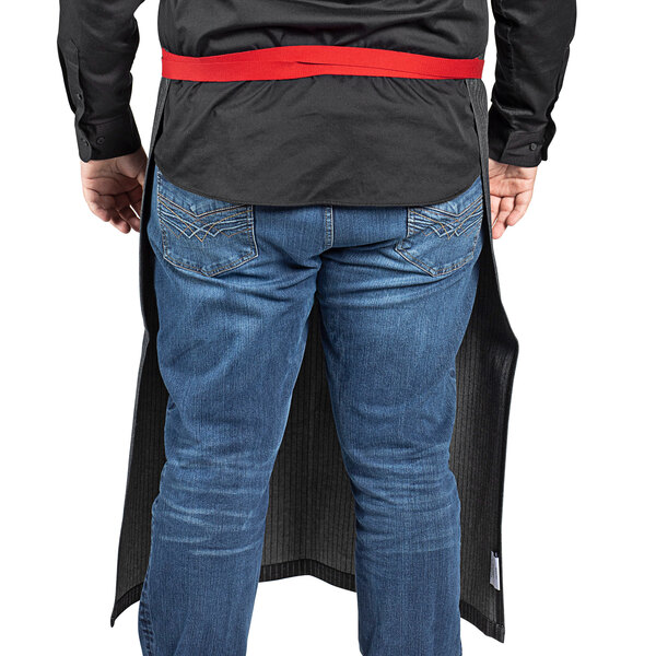 A man wearing a long black denim apron with red webbing.