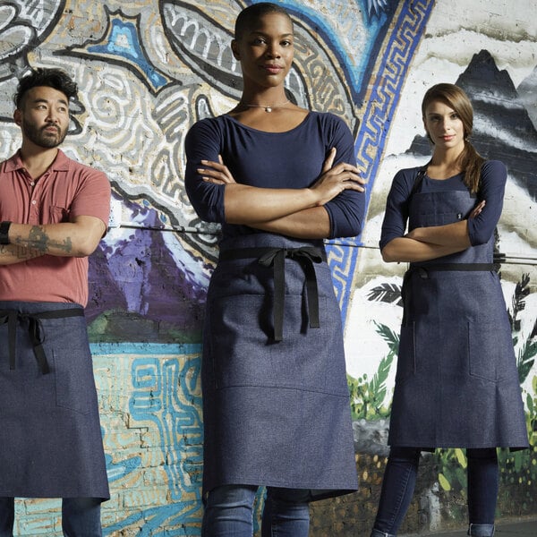 A woman wearing an indigo denim bistro apron with black webbing over a blue shirt.