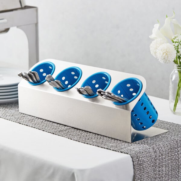 A Steril-Sil stainless steel flatware organizer with blue plastic cylinders holding silverware.