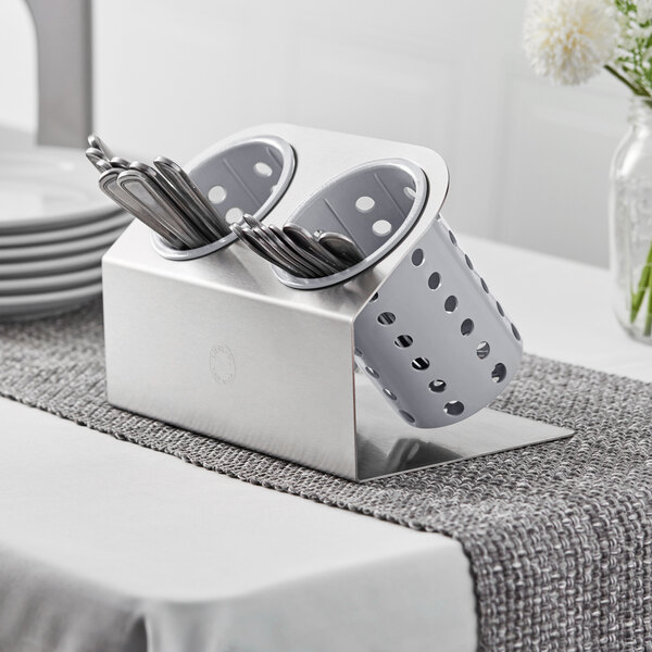 A Steril-Sil stainless steel flatware organizer with gray perforated cylinders holding spoons and forks.