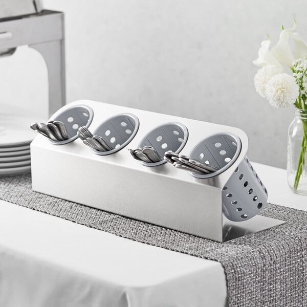 A Steril-Sil stainless steel flatware organizer with gray cylinders holding spoons and forks.