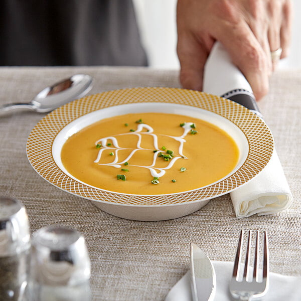 A close-up of a Visions ivory plastic bowl with soup and a spoon.