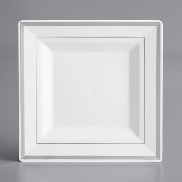 A white square Visions plastic plate with silver bands on a gray surface.