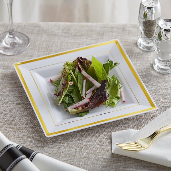 A plate of salad with greens and gold bands on a Visions white plastic plate.