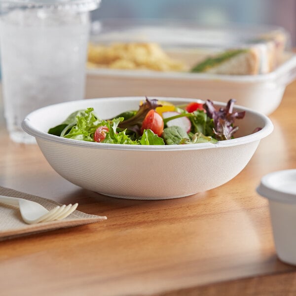 A bowl of salad with tomatoes and lettuce in a white Eco-Products WorldView bowl.