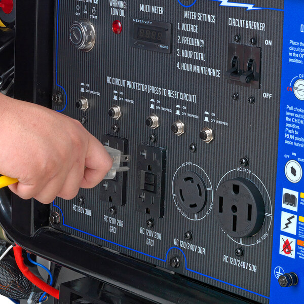 A person using a power cord to plug a DuroMax XP15000E generator into a yellow outlet.