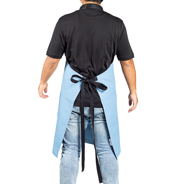 A man wearing a blue Uncommon Chef apron with black webbing.