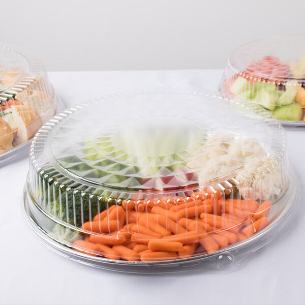 A Durable Packaging clear plastic high dome lid on a tray of vegetables and fruit in plastic containers.