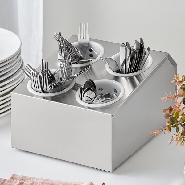 A stainless steel flatware organizer with perforated plastic cylinders holding silverware.