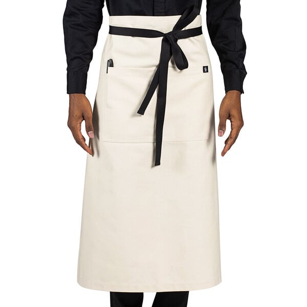 A person wearing a white Uncommon Chef Muse apron with black trim.