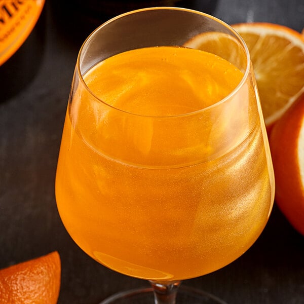 A glass of orange liquid with Spirdust shimmer on the table.