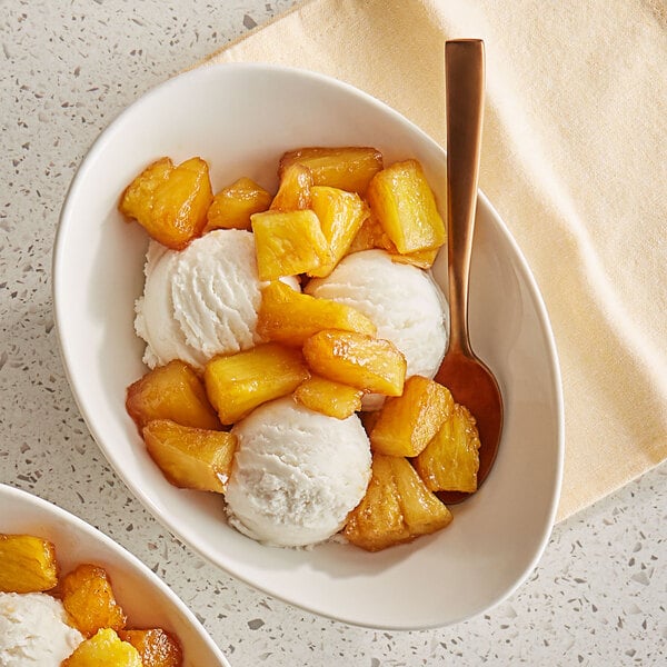 A bowl of ice cream with organic pineapple chunks on top.