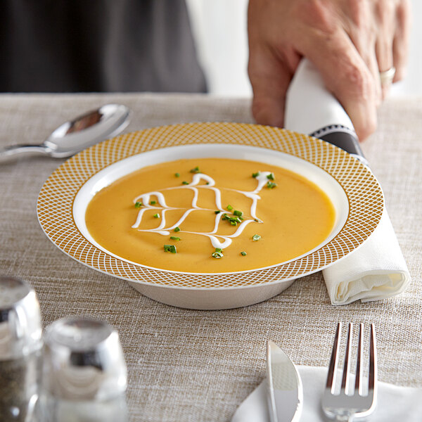 A hand holding a Visions plastic bowl of soup with white sauce and green onions.