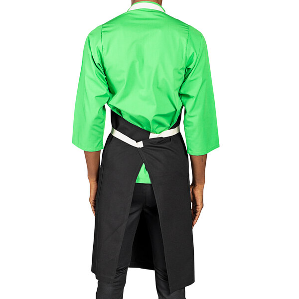 A man wearing a black Uncommon Chef Vibe bib apron with green accents.
