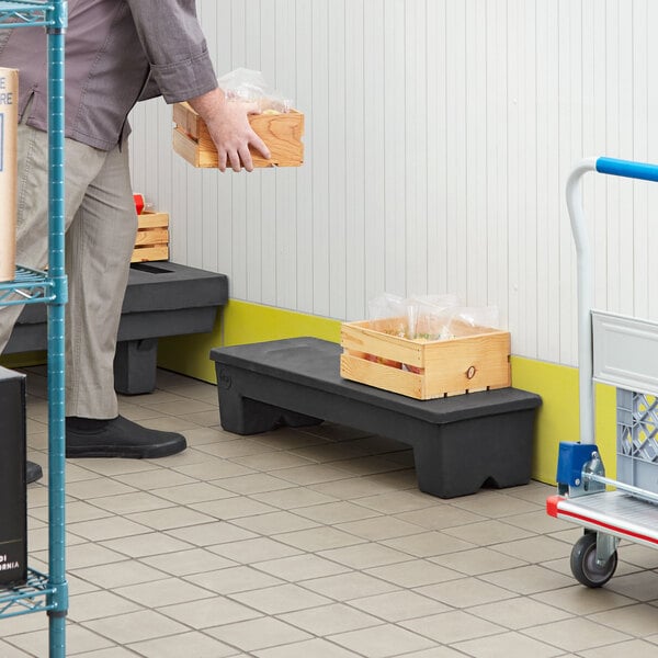 A man carrying a box of food on a white and grey plastic Regency narrow dunnage rack.