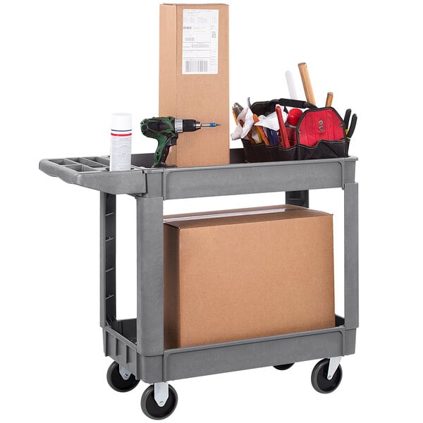 A Carlisle gray utility cart with tools and a box on a shelf.