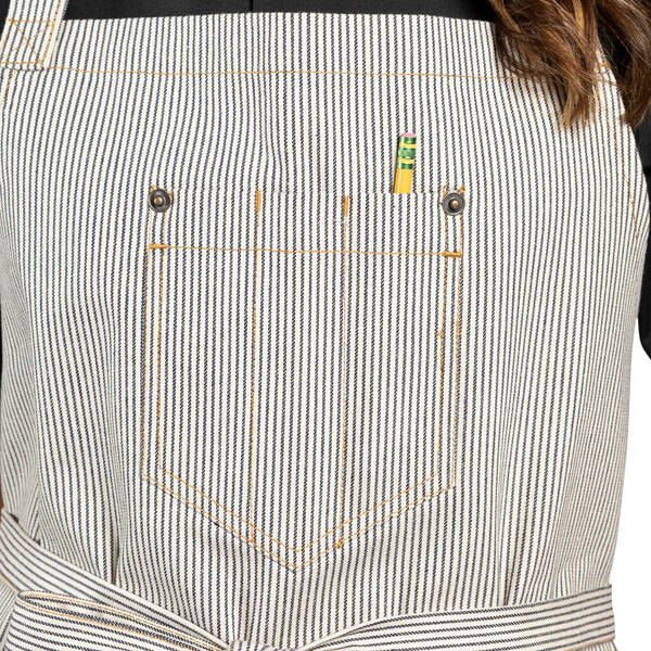 A woman wearing a denim apron with a striped towel loop and pockets.