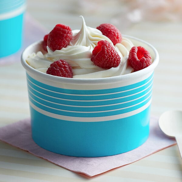 A blue paper Choice frozen yogurt cup filled with ice cream and raspberries.