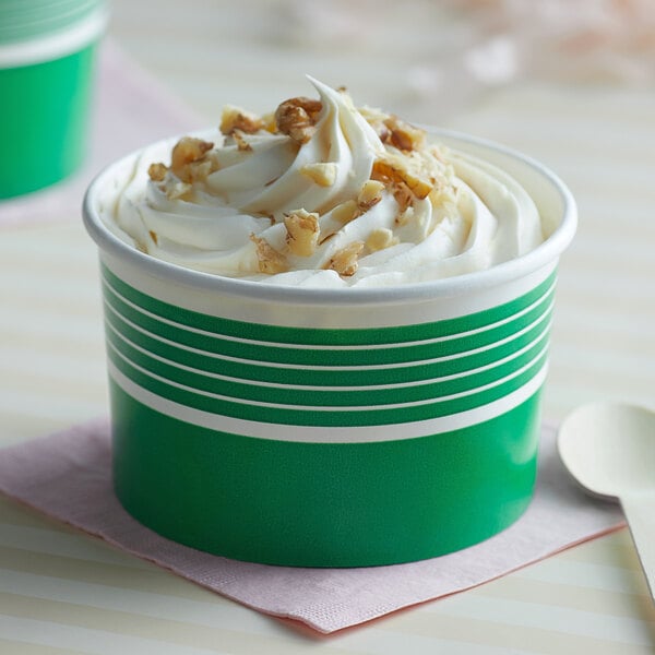 Two green Choice paper cups of frozen yogurt with white frosting and nuts on top.