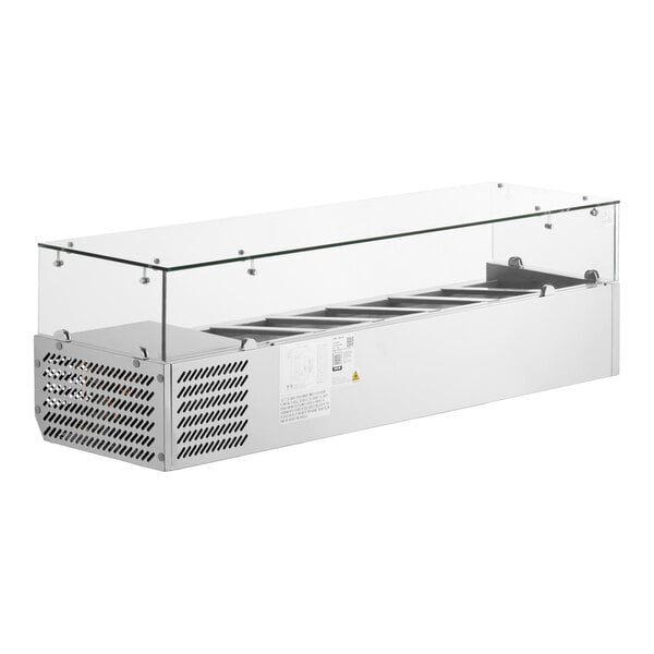 A stainless steel countertop refrigerated prep rail with a glass sneeze guard and multiple food pans.