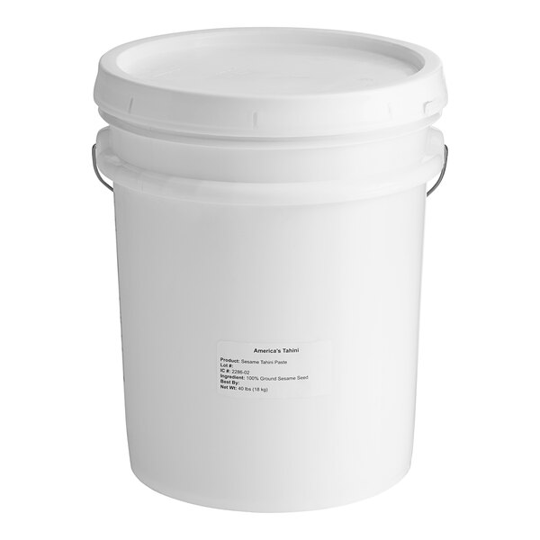 A white plastic pail with a lid and a label for Creamy Tahini Paste.