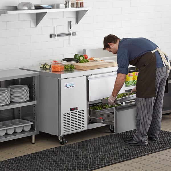 Employee putting a food pan into an Avantco refrigerator