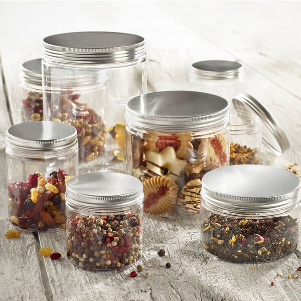 A group of Solia clear plastic jars with aluminum lids filled with different types of food.