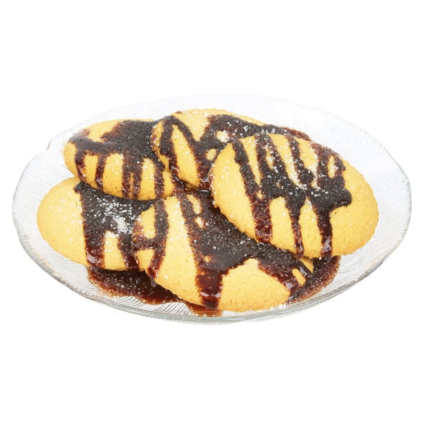 An Arcoroc Fleur glass dessert plate with cookies drizzled with chocolate sauce.