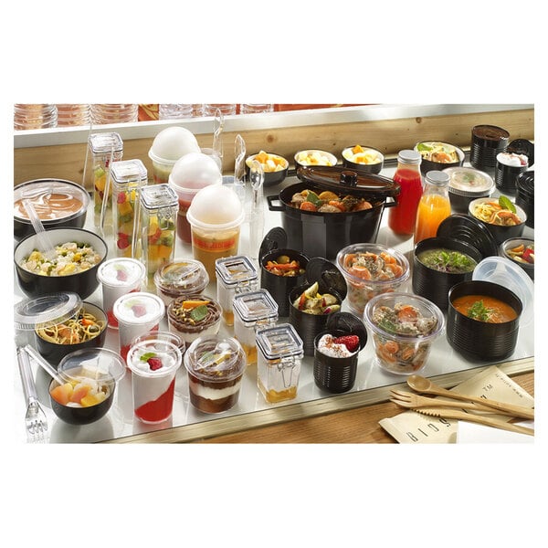 A table full of Solia clear plastic jars filled with food.