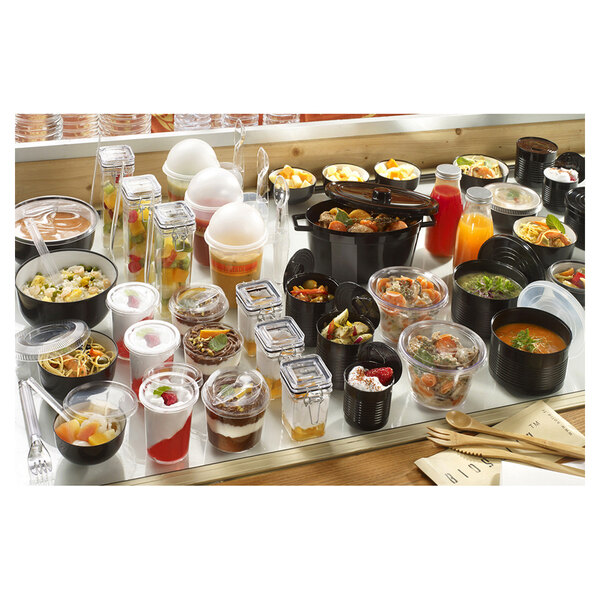 A table full of Solia black plastic tin cans filled with food.