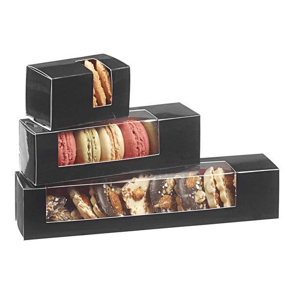 A stack of Solia black macaron boxes filled with macarons on a table.