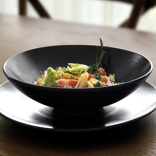 A Front of the House round black porcelain bowl filled with spiral ink pasta.