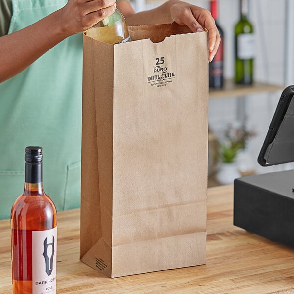 A woman pouring wine from a bottle into a Duro brown paper bag.