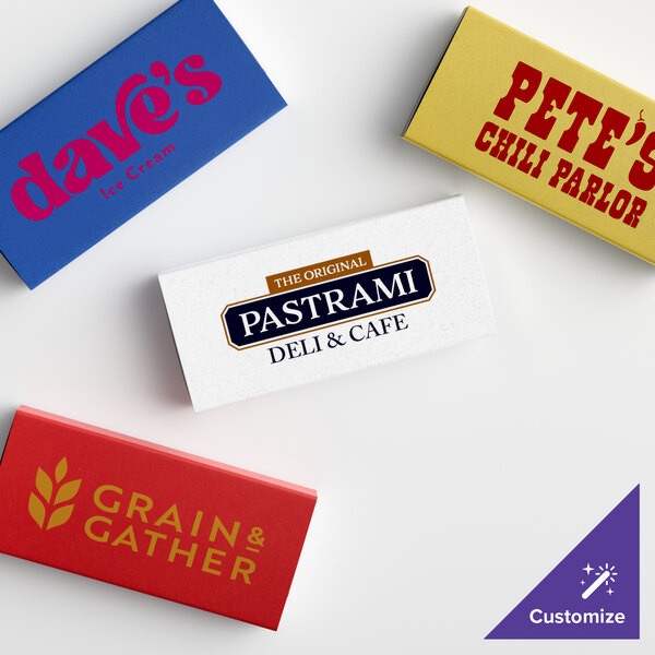 A group of red rectangular custom printed toothpick boxes with gold text on a counter.