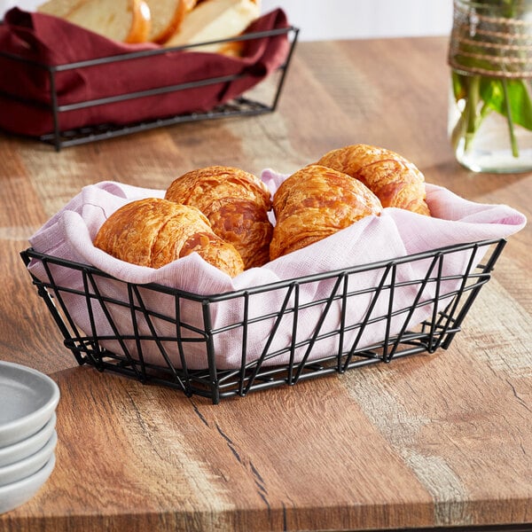 An American Metalcraft black rectangular basket filled with croissants on a table.