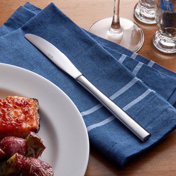 Stainless steel dinner knife on a blue cloth napkin