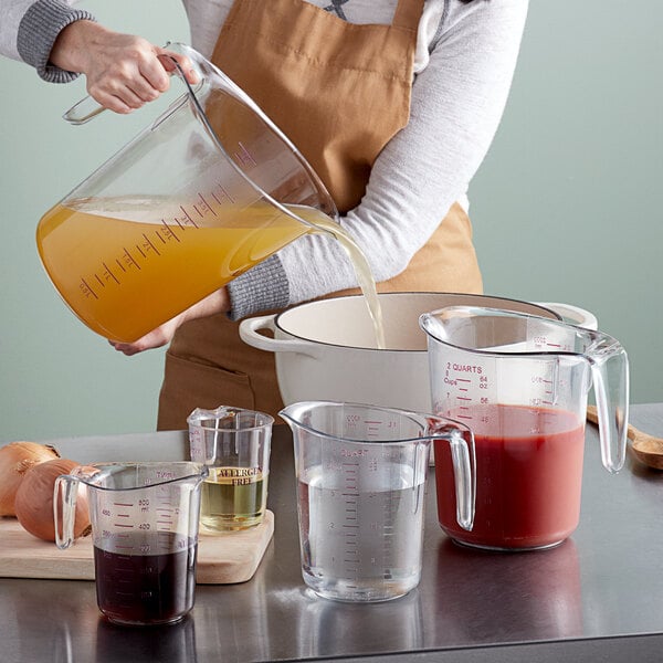 A woman using a purple plastic measuring cup to pour liquid into it.