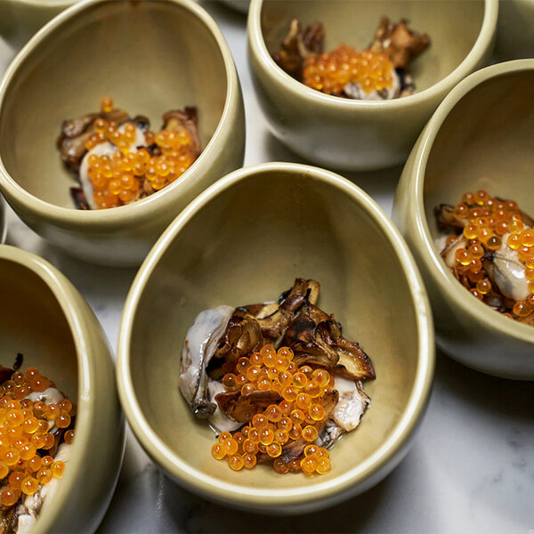 A group of Front of the House Tides sea grass bowls filled with orange fish eggs.