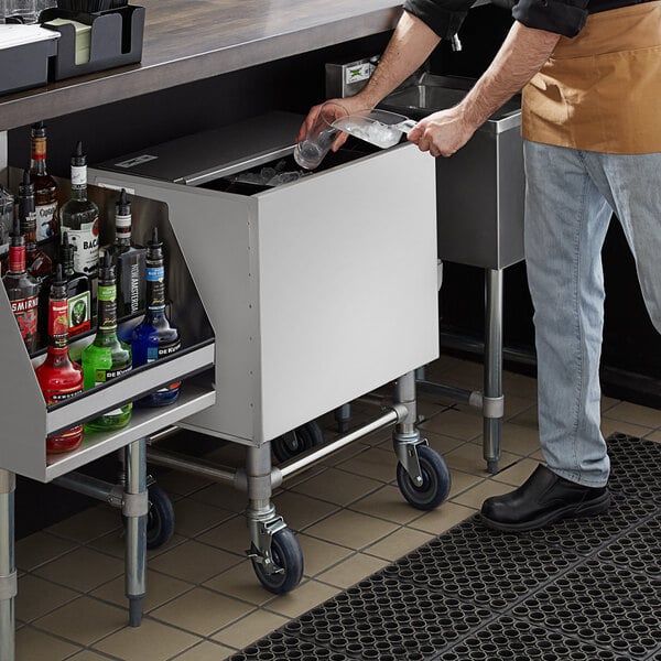 A man using a Regency stainless steel ice bin on a counter in a cocktail bar.